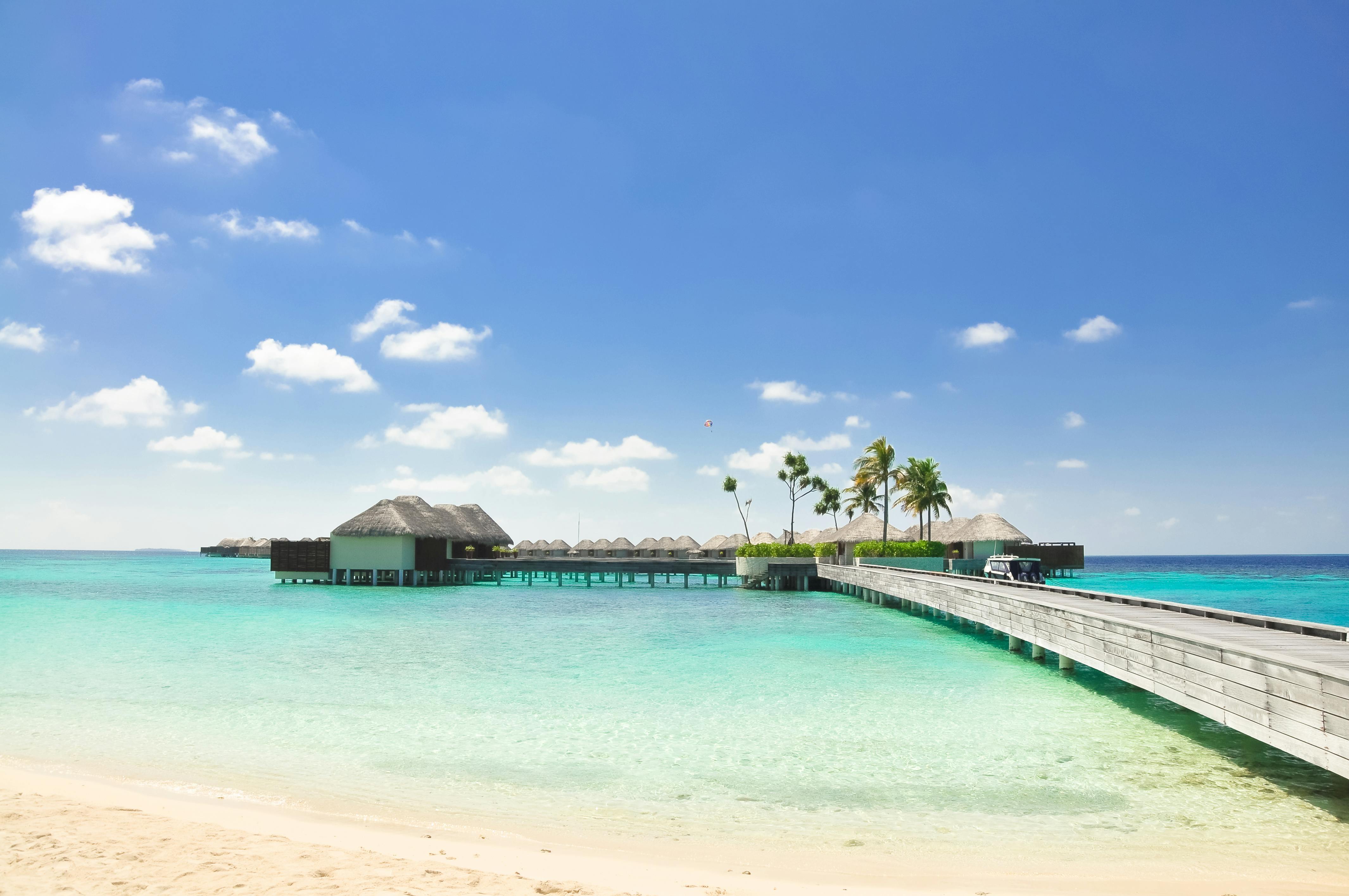 阳光明媚的日子里，美丽的热带海滩上有一座通往豪华水上别墅的木桥