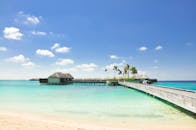 阳光明媚的日子里，美丽的热带海滩上有一座通往豪华水上别墅的木桥