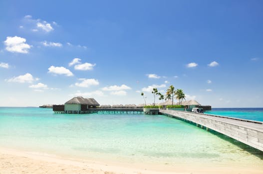 阳光明媚的日子里，美丽的热带海滩上有一座通往豪华水上别墅的木桥