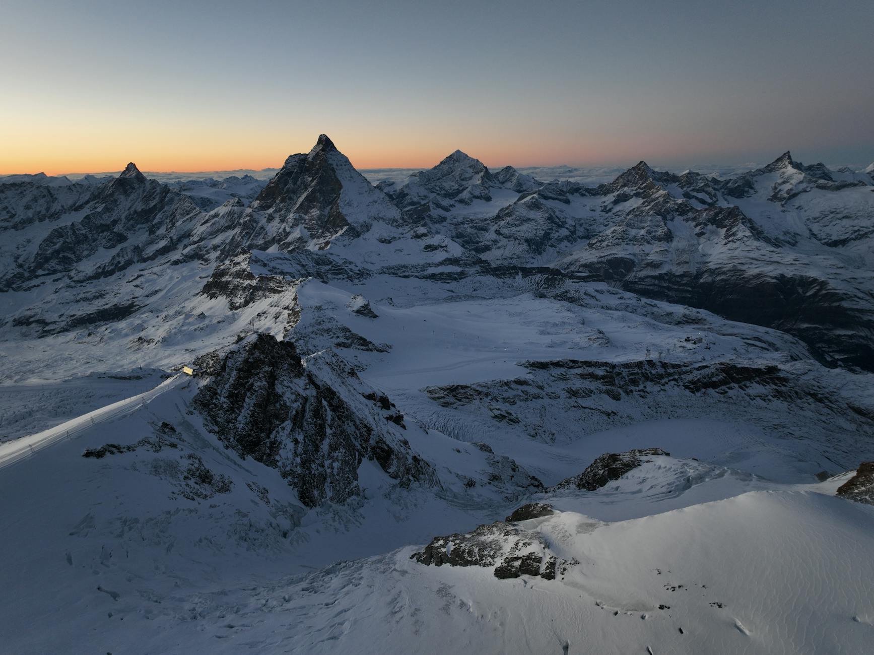 A breathtaking aerial view of snow-covered Matterhorn and surrounding peaks at sunrise in Zermatt, Switzerland.