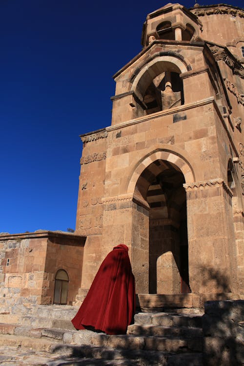 Person in Maroon Robe Entering a Church