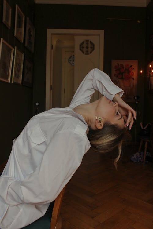 A Woman in White Long Sleeves Sitting with Her Head Up