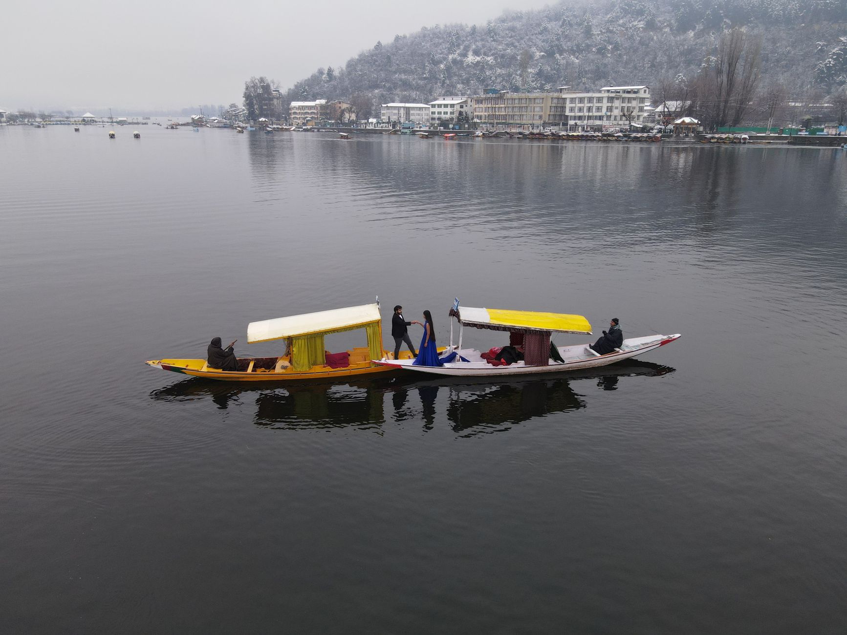 Couple enjoying a romantic shikara ride on a serene winter lake in Srinagar, showcasing local culture.