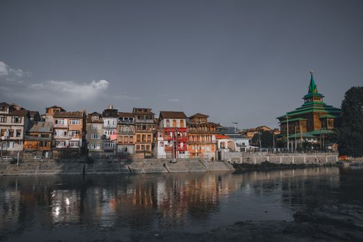 Charming old buildings by a tranquil river, reflecting a serene and vibrant evening atmosphere.