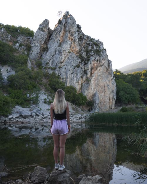 Free A woman stands by a tranquil lake, admiring the rocky mountain landscape. Stock Photo
