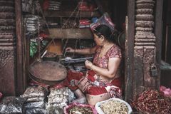 A woman vendor in traditional attire weighs spices at a vibrant street market, rich in cultural textures.