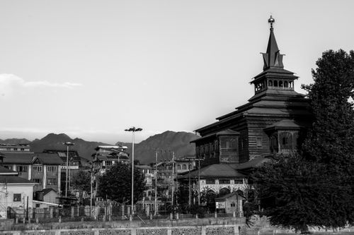 Free Black and white image of a historic mosque in Srinagar with majestic mountains in the background. Stock Photo