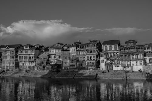 Grayscale Photo of Buildings by a Riverside
