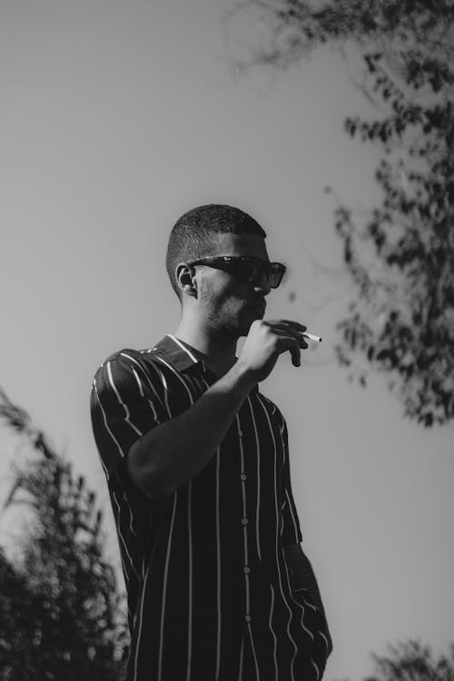 A Man Wearing Sunglasses While Smoking 