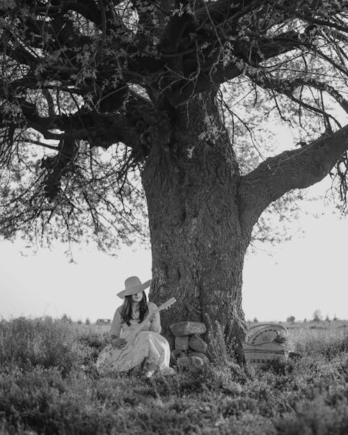 Grayscale Photo of Woman Sitting Under a Tree