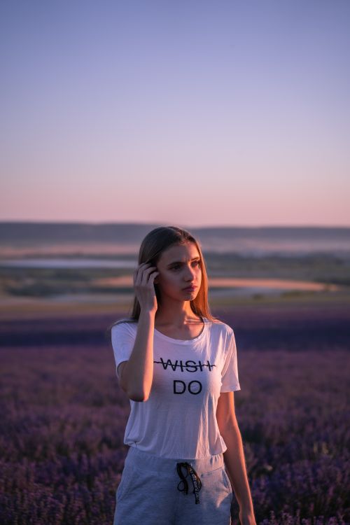 Free Woman standing in a lavender field during sunset, wearing a 'Wish Do' shirt. Stock Photo