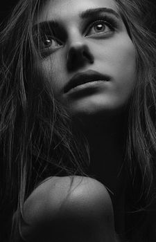 Close-up black and white portrait of a woman with contemplative expression.