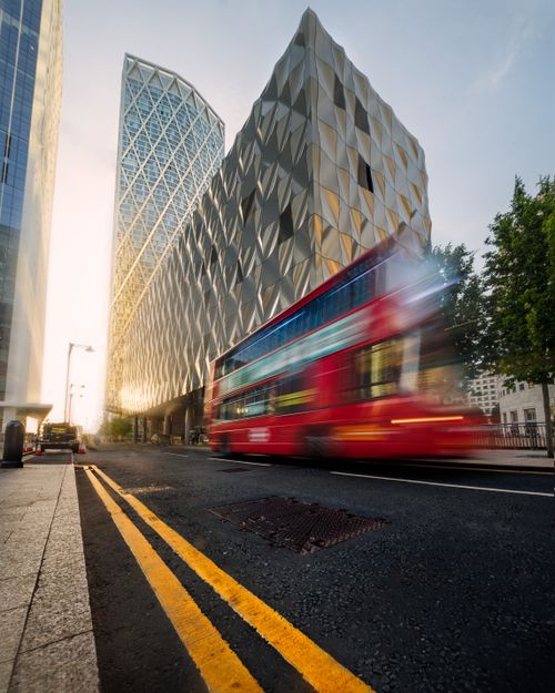 Free A blurred red double-decker bus speeds past modern architecture in an urban cityscape. Stock Photo