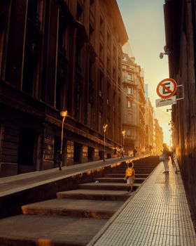 A pedestrian street in Buenos Aires, Argentina, at sunset with dramatic shadows and warm light.