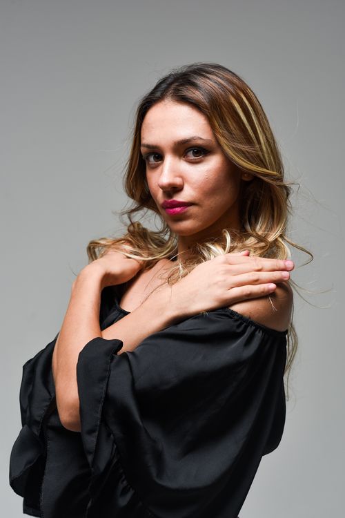 Free A striking portrait of a blonde woman crossing her arms against a gray background. Stock Photo