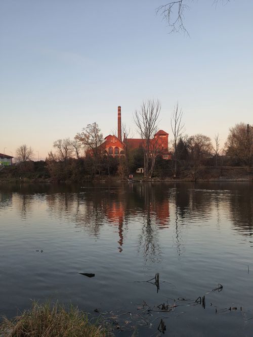 Free Scenic view of a historic building reflecting in the calm river during fall in Wrocław, Poland. Stock Photo