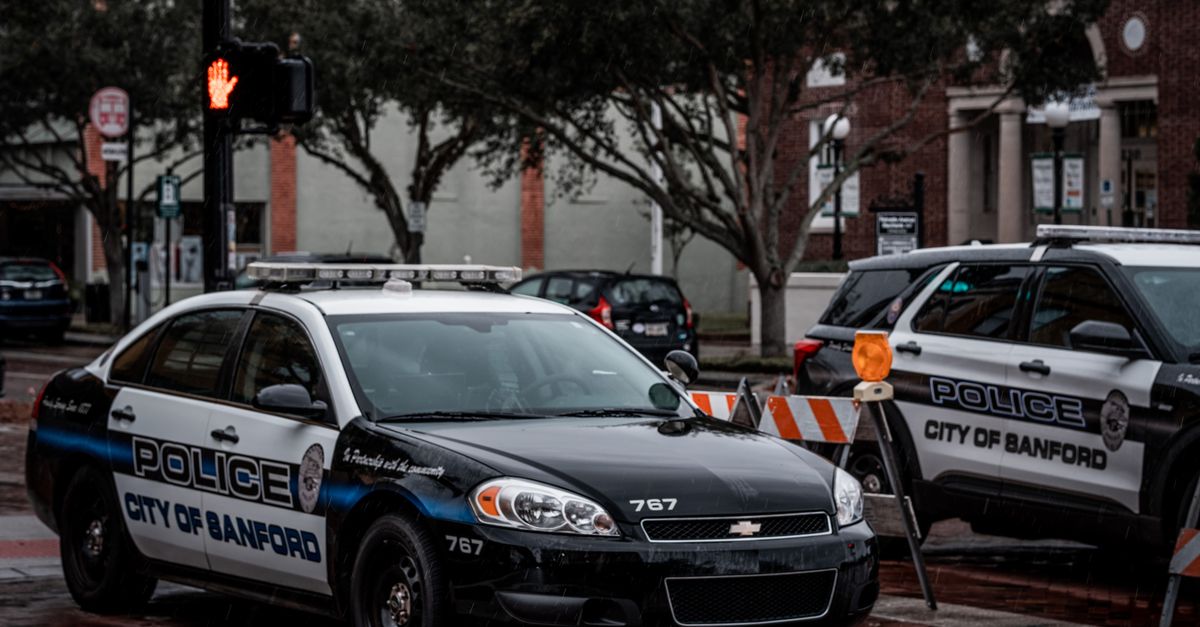 City of Sanford police cars parked on wet urban streets with traffic signals and buildings.