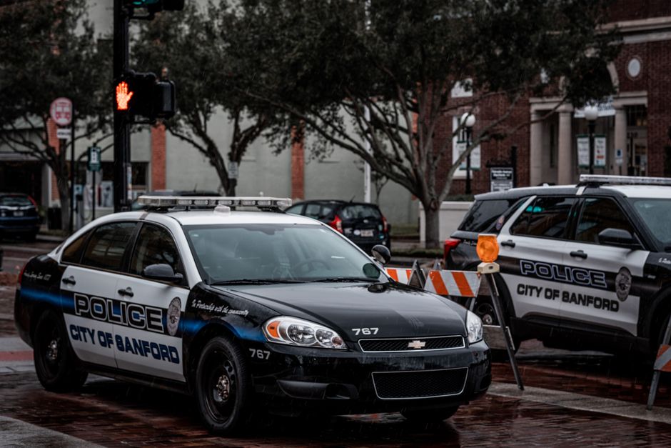 As City Of Boca Raton Seeks New Police Chief, Public Invited To Share Thoughts 2 City of Sanford police cars parked on wet urban streets with traffic signals and buildings. | BocaVibe