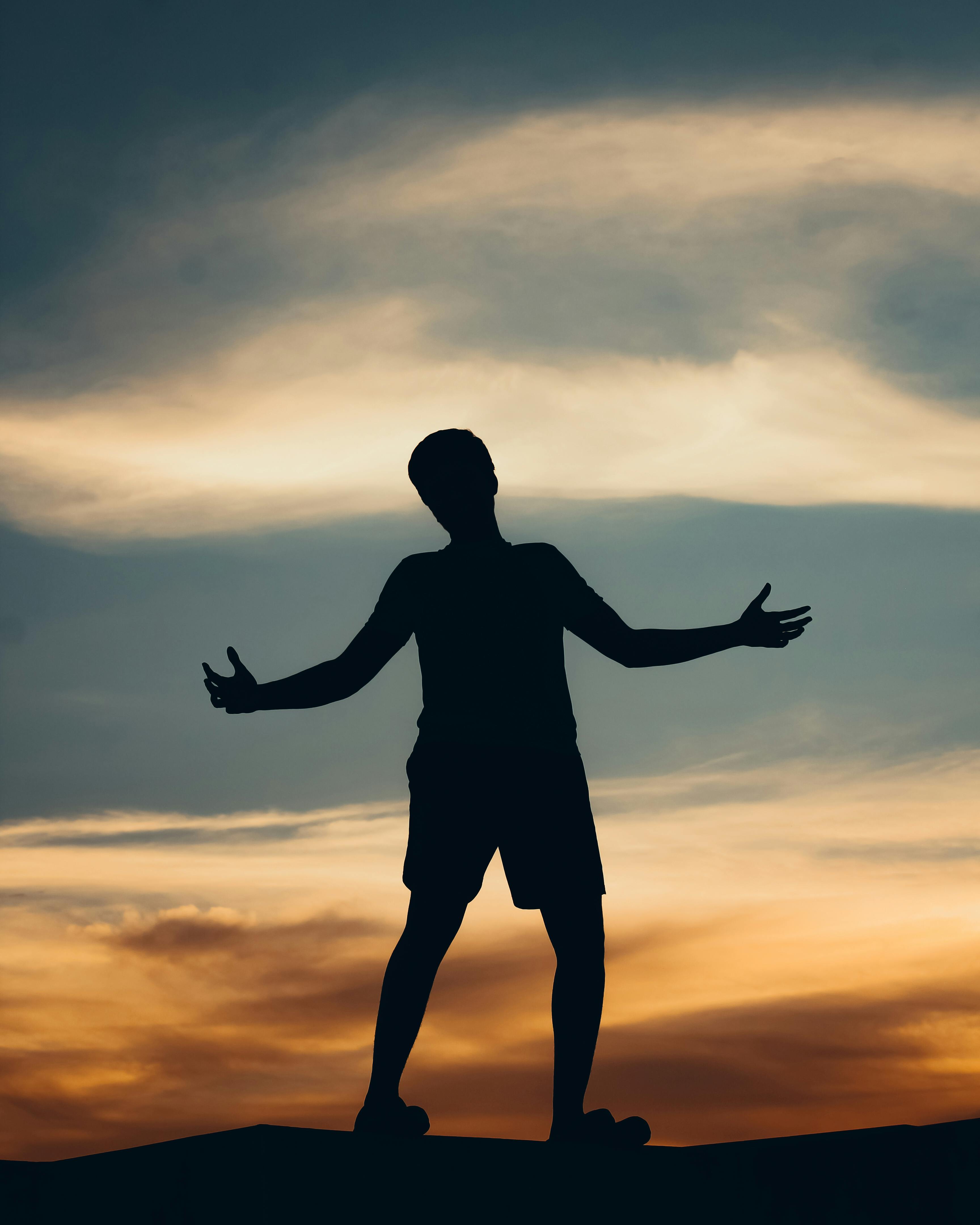 Silhouette of man stretching out arms, against clear sky stock photo