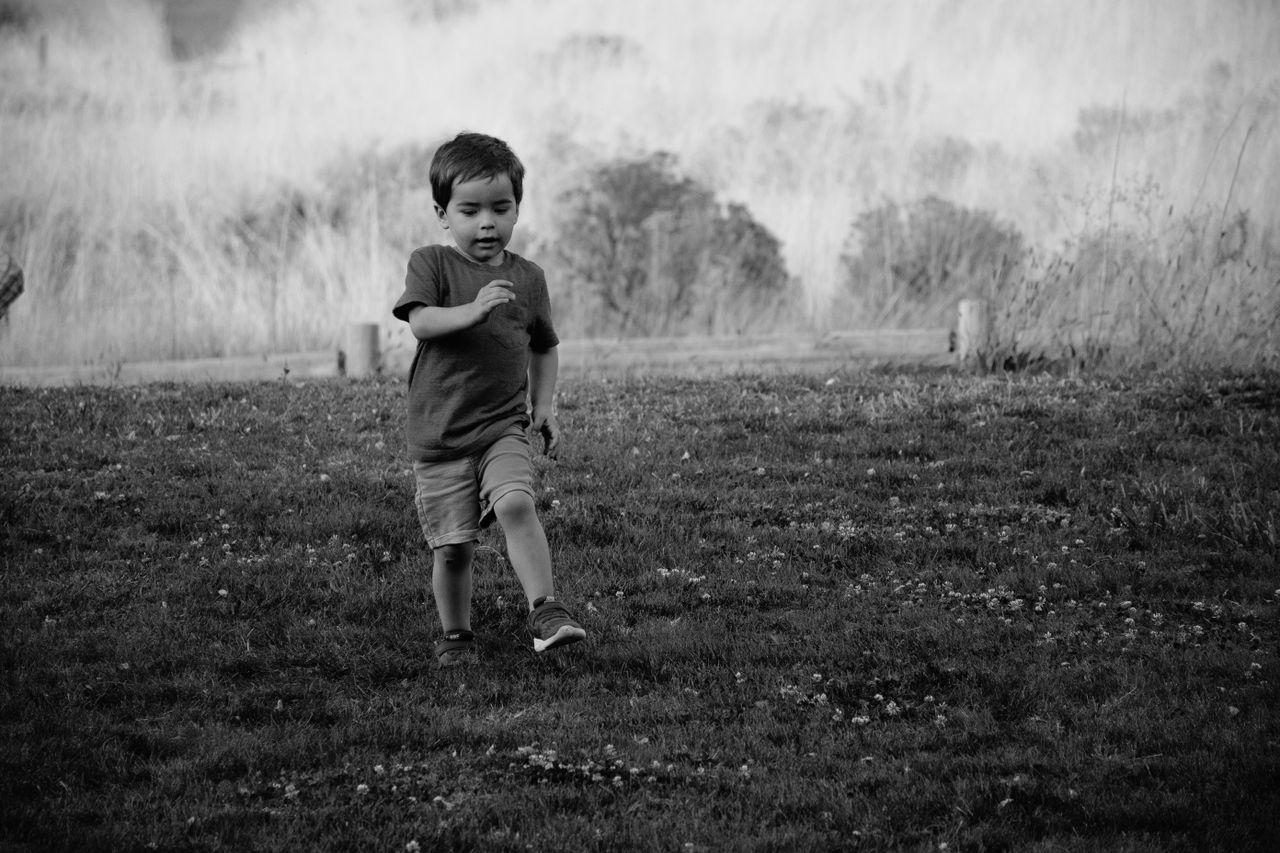 a young child joyfully running in a grassy field in monochrome