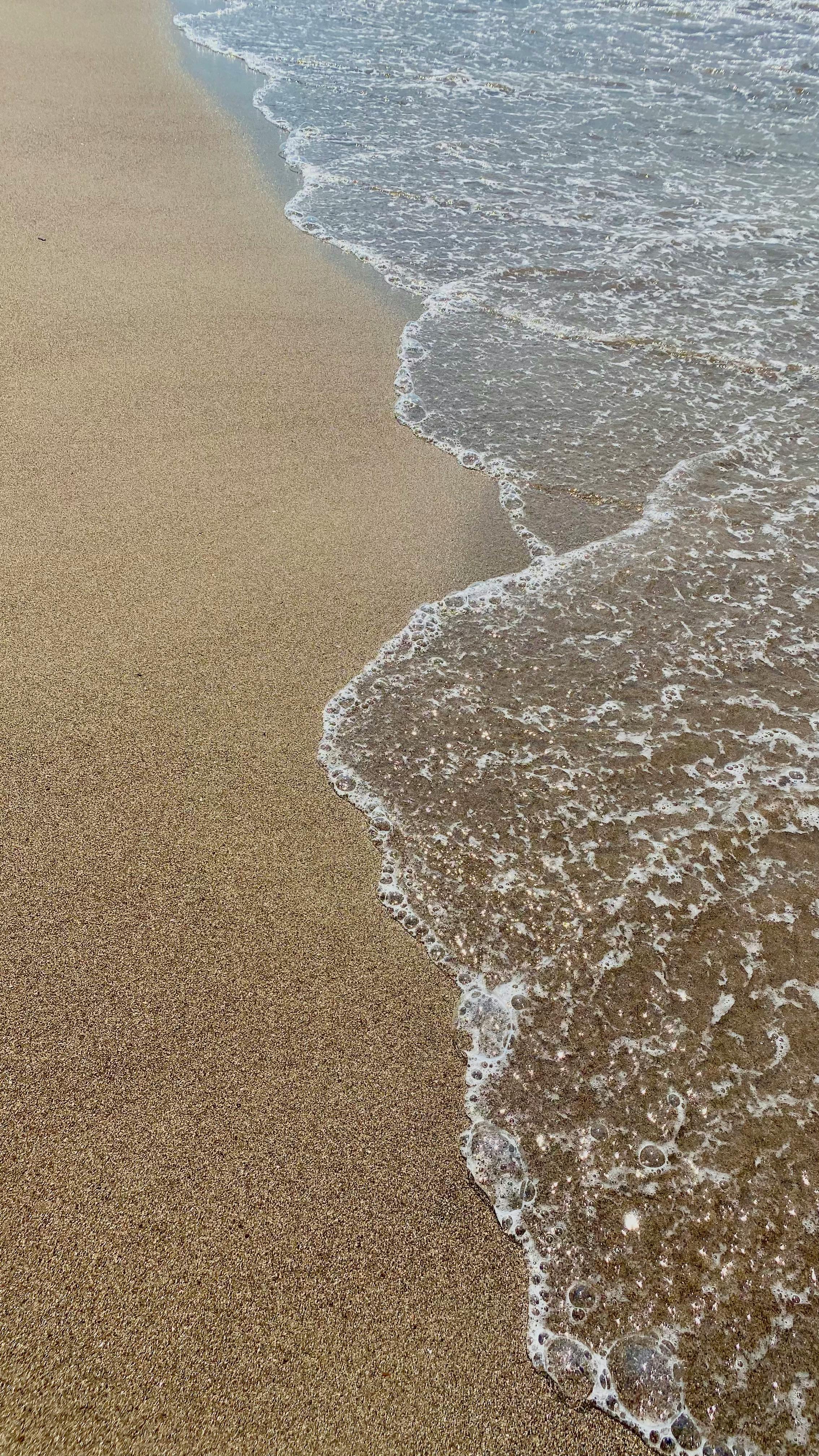 Serene view of gentle ocean waves lapping a sandy beach, inspiring calmness and relaxation.