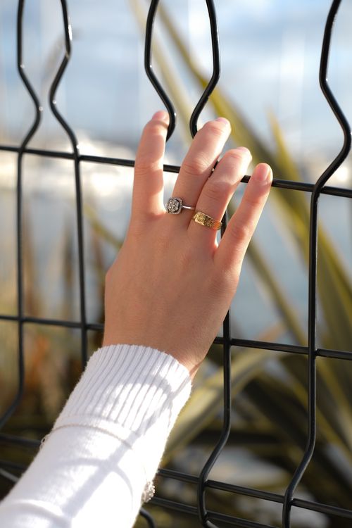 Free Close-up of a woman's hand with rings gently touching a metal fence outdoors. Stock Photo