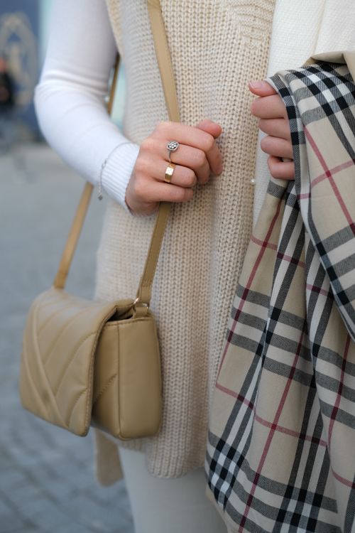 Free Close-up of a stylish woman holding a scarf and bag, showcasing fall fashion trends. Stock Photo