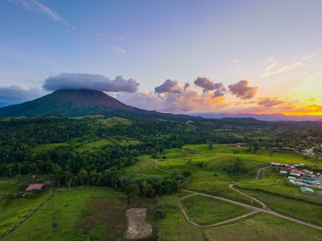 Breathtaking aerial view of Arenal Volcano at sunset in Alajuela Province, highlighting lush landscapes.