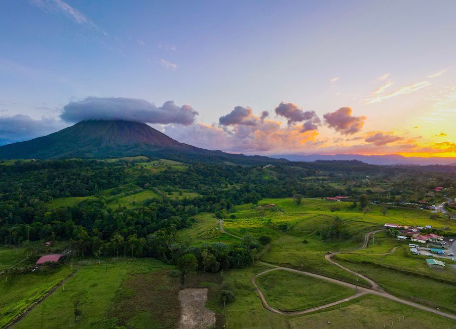 Breathtaking aerial view of Arenal Volcano at sunset in Alajuela Province, highlighting lush landscapes.