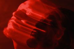 Artistic double exposure of a man with a red blurred motion effect, conveying emotion.