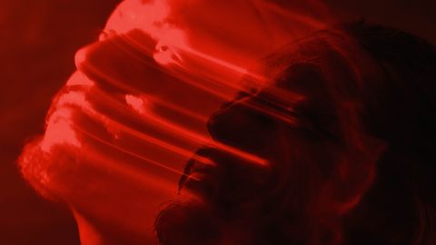 Artistic double exposure of a man with a red blurred motion effect, conveying emotion.
