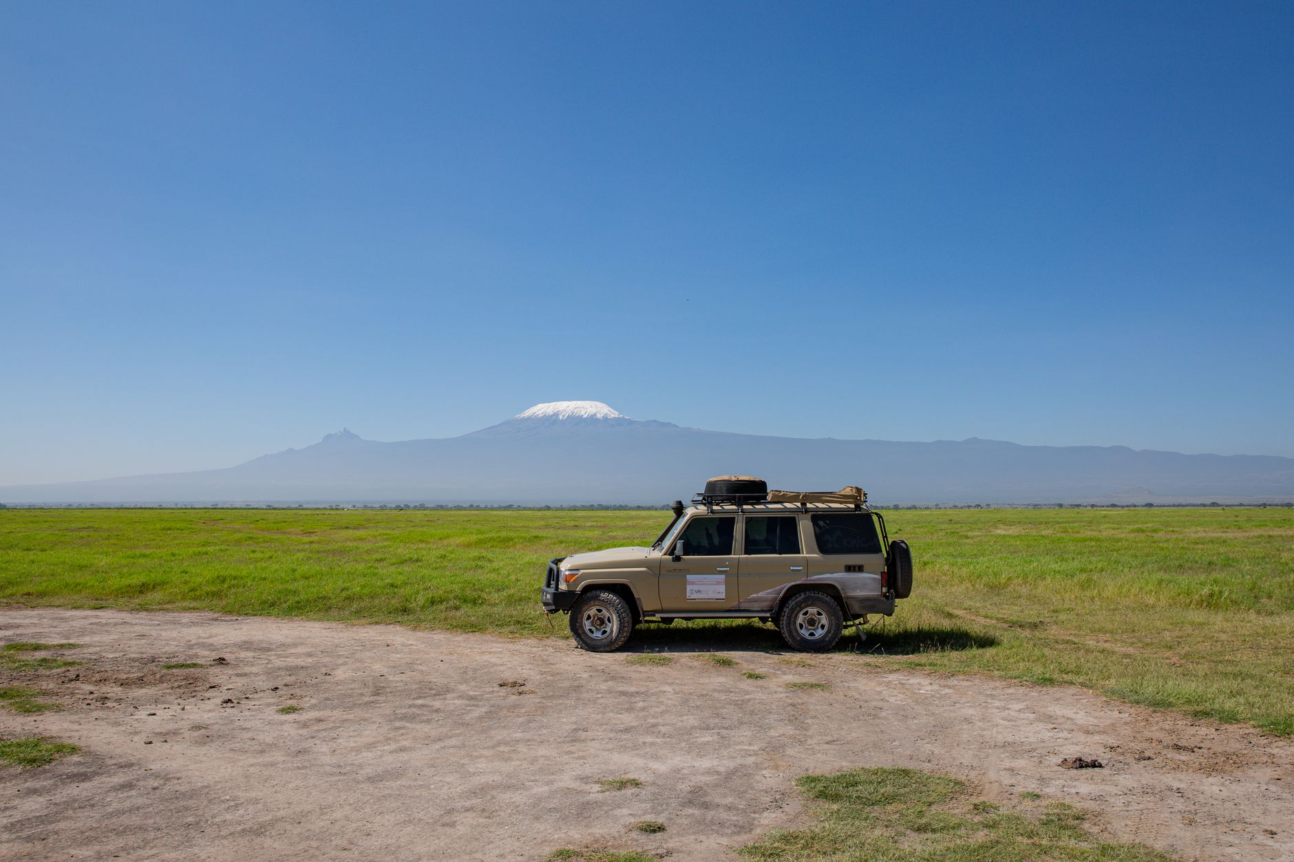 A 4x4 vehicle parked on a savannah with Mount Kilimanjaro in the background, highlighting adventure and exploration.