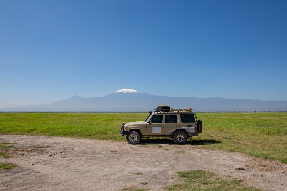 safari vehicle, dirt track, open savannah, clear blue sky