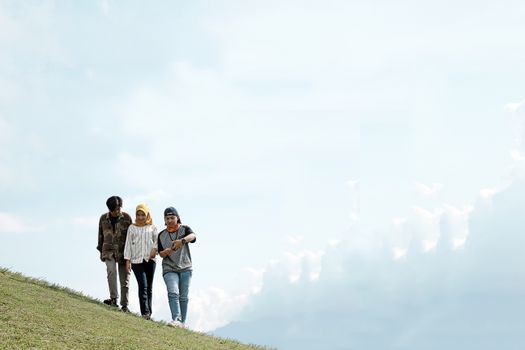 三个朋友在明亮的天空下，走在绿草如茵的山坡上，享受户外活动