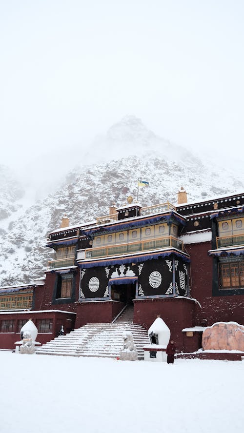 Facade of a Tibetan Monastery, and a Snowy Mountain in Fog