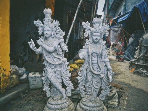 Free White Hindu deity statues stand in an urban alley, showcasing intricate design and religious significance. Stock Photo