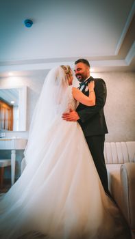 A joyful bride and groom lovingly embrace at their indoor wedding ceremony.