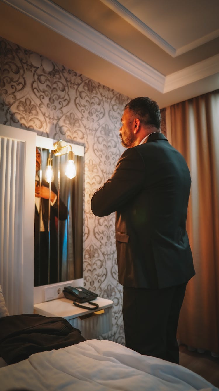 A Man In Black Suit Looking At The Mirror