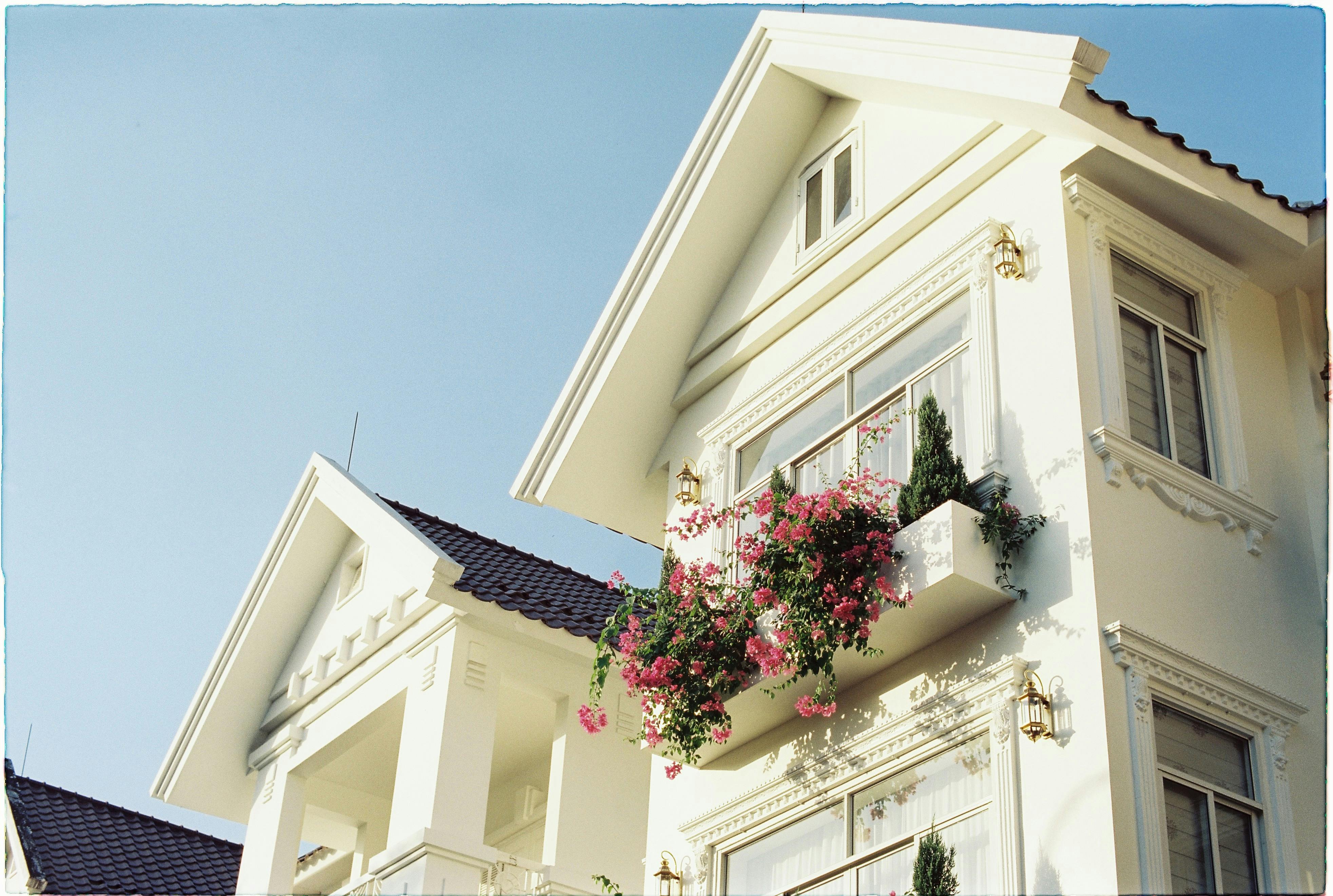 Bright facade featuring flowers on a sunny day, capturing elegant architecture.