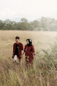 夏天，幸福的情侣手拉手走过绿草如茵的田野