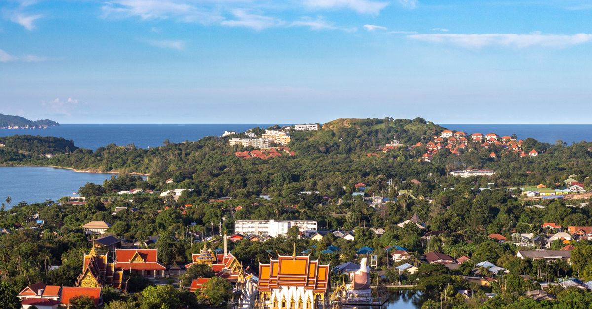 Aerial view of a coastal city featuring a bright temple and lush greenery.