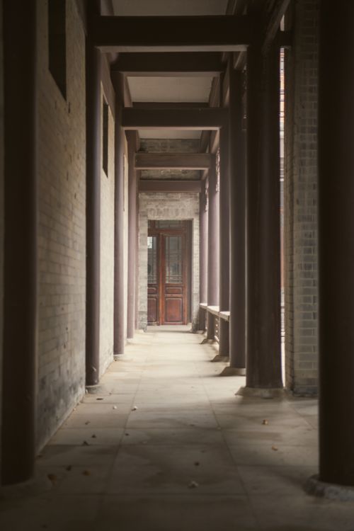 Free A serene empty hallway featuring archways and wooden door. Atmospheric lighting and peaceful mood. Stock Photo