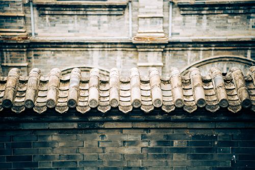 Free Close-up of an ornate traditional Asian roof with detailed tiles and textured wall. Stock Photo