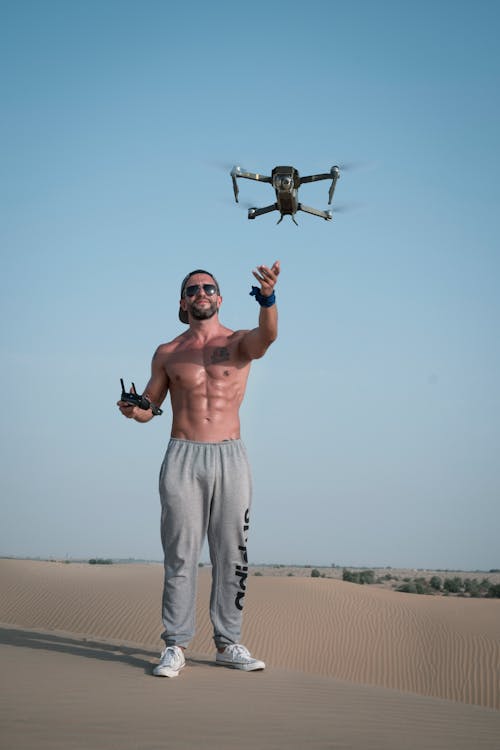 Free Man Holding Drone Remote Standing on Gray Concrete Pavement Stock Photo
