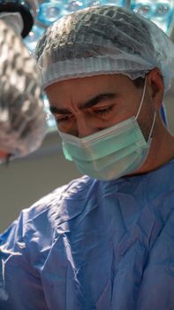 Close-up of a focused surgeon wearing a surgical mask and cap during a medical procedure.