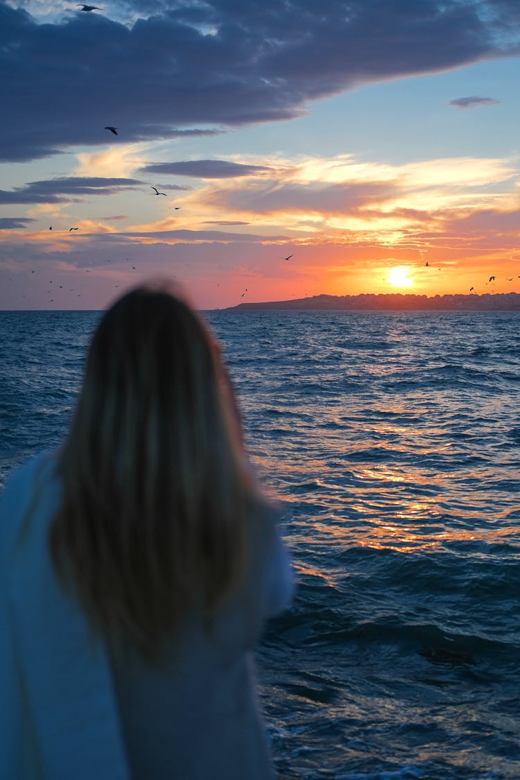 Woman Watching A Sunset Over The Sea