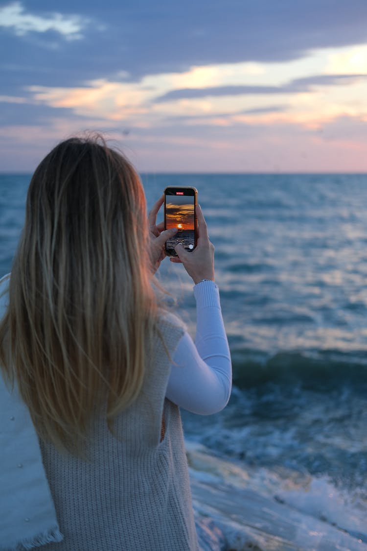 Woman Photographing Sunset At The Sea With Her Smart Phone