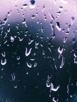 Close-up of raindrops on a window with a navy blue background, capturing a serene, rainy day mood.