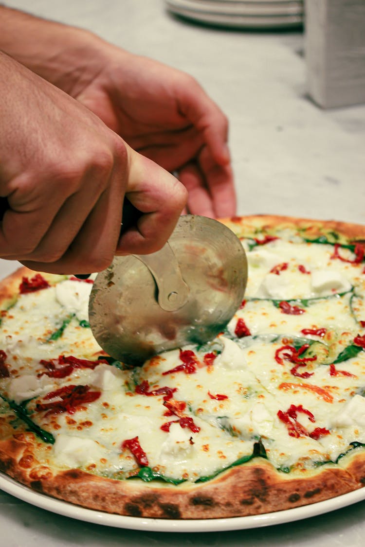 Person Slicing Homemade Pizza