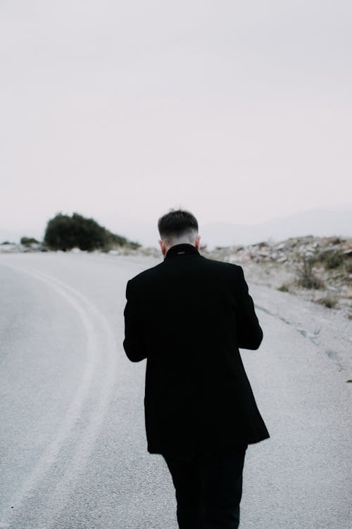 Back View of Man in Black Suit Standing on Road